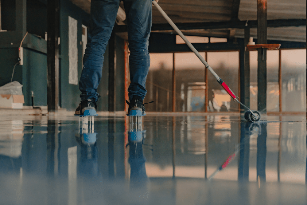 The worker applies gray epoxy resin to the new floor